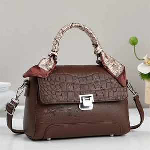 Brown leather handbag with crocodile flap, silk scarf handle, and silver buckle closure