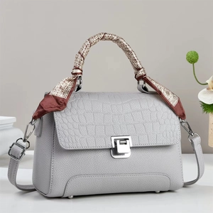 Detail of grey crocodile and lychee leather handbag with silver lock and silk scarf handle