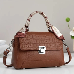 Detail of dark brown tote bag with crocodile embossing, silver lock, and silk scarf