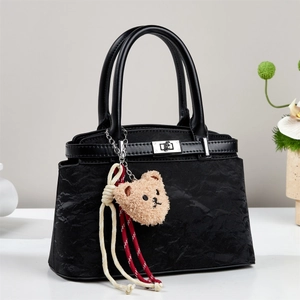 Fashionable black pleated crossbody bag with silver lock and plush bear pendant