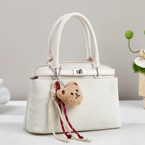 Detail of off-white tote bag with marble pattern, silver clasp and cute bear charm