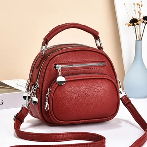 Detail view of burgundy pebble leather mini bag with silver hardware and zipper pockets