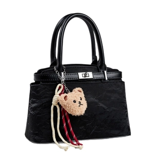 Quilted black tote bag with silver clasp, plush bear charm and woven cord accent