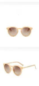 Detail of oval beige frames with golden metal temples and dark brown UV400 lenses