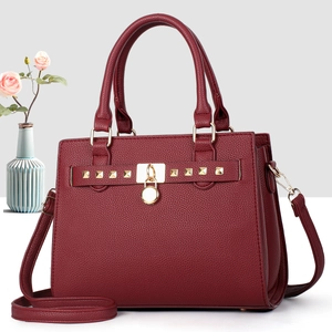 Dettaglio borsa bordeaux in pelle martellata con finiture dorate e borchie quadrate