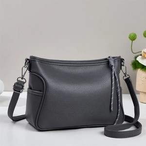 Détail du cabas en cuir litchi gris foncé avec pendentif tressé et garnitures en métal