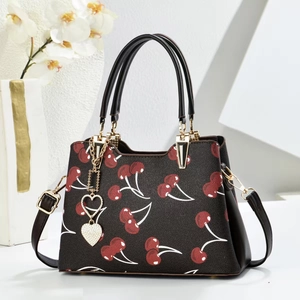 Elegant brown top handle bag with red cherry prints and heart-shaped charms