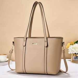 Dettaglio ravvicinato di una grande borsa tote beige con placca dorata in casa