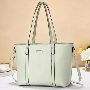 Dettaglio borsa tote verde menta con barra dorata e tracolla rimovibile