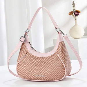 Straw hobo bag with pink leather trim and adjustable strap in studio setting