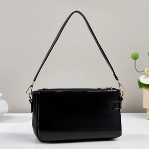 Glossy black patent leather shoulder bag detail with adjustable strap and metallic buckle
