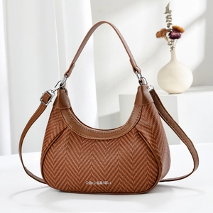 Detailed view of brown herringbone weave crescent bag with silver logo and leather trim