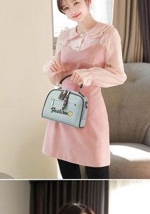 Model wearing a mint blue crossbody bag with brown handles and a front zipper pocket