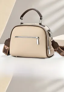 Rear view of beige handbag showing the back zipper pocket and brown handle with wide strap