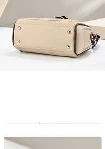 Detail of beige handbag bottom featuring silver protective studs and brown edge finish