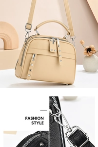 Detail of pebbled leather texture, dual zippers and silver rivets on women's handbag
