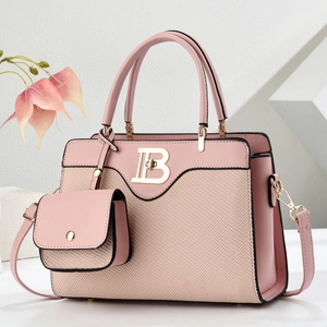 Bolso de mano rosa con diseño patchwork, logo dorado y correa sobre fondo blanco