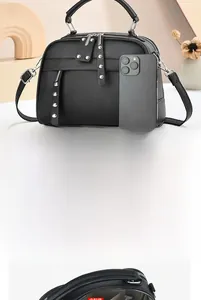 Detail of black lychee-textured crossbody bag showing double zipper and internal storage