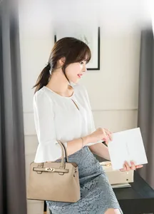 Detail view of the beige lychee pattern tote bag featuring gold-tone turn-lock hardware