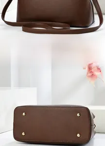 Detail view of coffee brown lychee grain leather handbag showing back and metal feet studs