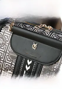 Detail der goldenen Logoplatte und Metallbeschläge an schwarzer Lederhandtasche