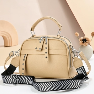 Minimalist beige crossbody bag with textured leather, wide strap, and silver rivets