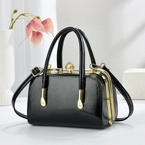Gros plan du sac à main noir texture serpent avec cadre doré et fermoir perle chic