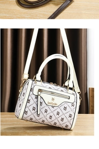 Detail of cream Boston bag featuring embossed logos and elegant gold-tone hardware accents