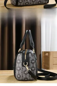 Detail of Boston bag showing monogram pattern, gold hardware, and sturdy black handles