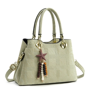 Detail of sage green embossed leather handbag featuring geometric texture and star charm