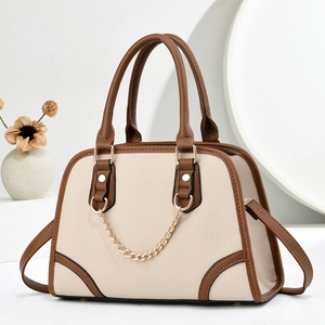 Detail of elegant two-tone handbag with golden chain and pebble leather texture
