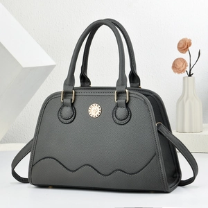 Grey lychee texture tote bag with wave stitching and gold emblem on white stone