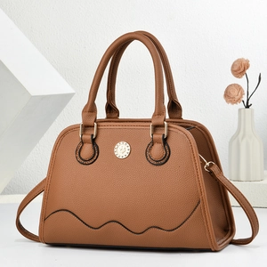 Minimalist warm brown pebble leather tote bag with gold hardware on white display pedestal