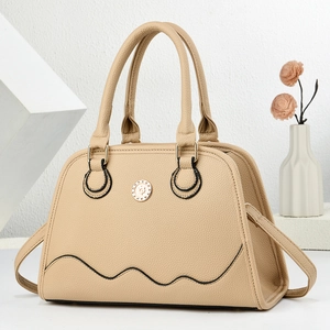 Detail of beige lychee textured tote bag featuring wavy black lines and a gold metal buckle