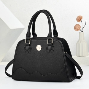 Detail of black pebbled leather tote with wavy stitching and golden emblem accent