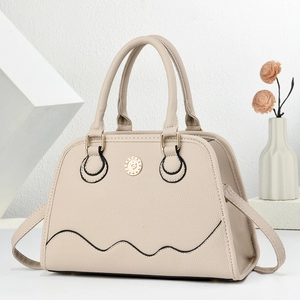 Detail of beige pebble leather handbag showing gold logo and shell-shaped design