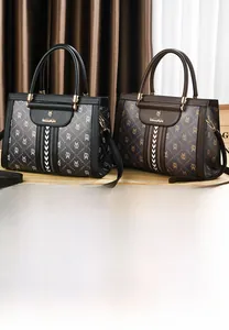 Detail of classic black and brown monogram satchel bags with gold logo and dual handles