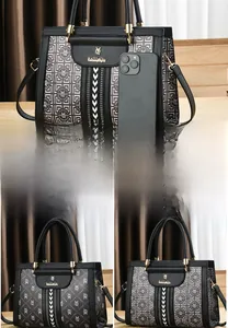 Detail view of black soft leather tote bag with gold hardware and phone for size reference