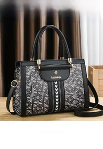 Detailed front view of black leather handbag with branded logo print and gold hardware