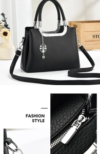 Detail of black lychee grain leather handbag with silver hardware and petal pendant