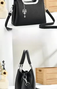 Detail of black lychee grain leather handbag with silver handle and leaf pendant charm