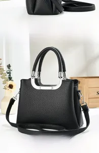 Macro detail of black litchi textured leather handbag with elegant silver metal handles