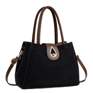 Elegant black woven handbag with brown leather straps and gold teardrop clasp detail