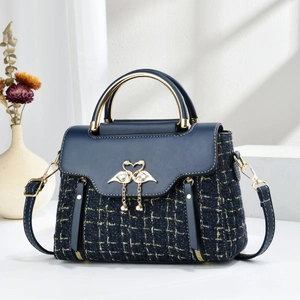 Details einer blauen Tweed-Handtasche mit goldener Flamingoschnalle und Quastenanhänger