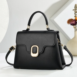 Detail of black litchi texture leather handbag with elegant oval gold metal buckle
