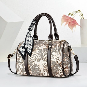 Vue détaillée du sac Boston avec imprimé tropical crème et poignées en cuir marron