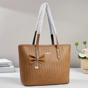 Détail d'un sac cabas marron tissé avec charme de perle et poignées doubles élégantes