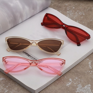 Three pairs of vintage cat eye sunglasses in red, brown, and pink on a white book