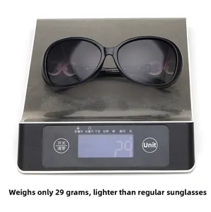 Detail view of large black sunglasses showing lightweight 29g frame on digital scale