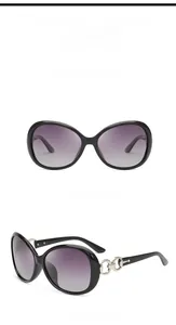 Detail of oversized black sunglasses featuring purple gradient lenses and metal chain temples
